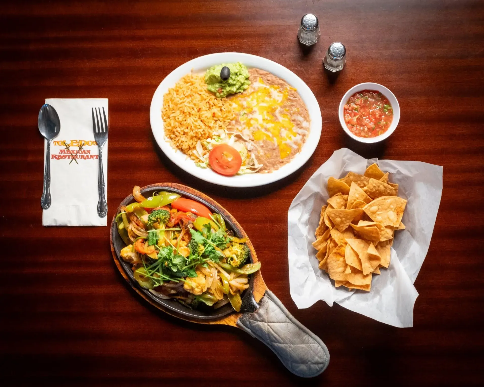Fajita skillet with rice, beans, and chips arranged for Mexican takeout