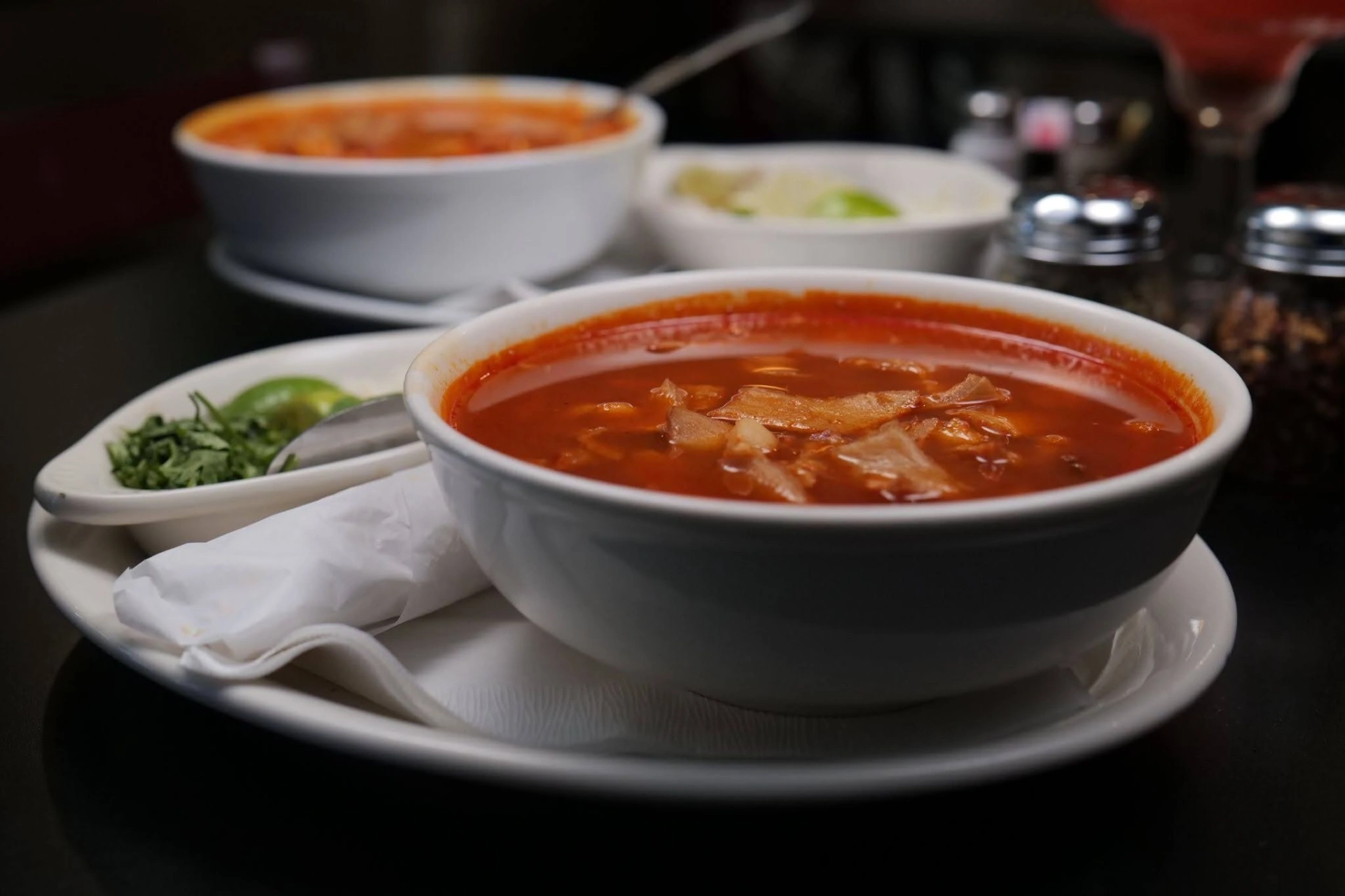 Bowl of Mexican menudo soup garnished with cilantro and lime